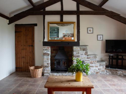 a living room with a fireplace and a wooden table at Honeysuckle Cottage - Ukc4692 in Kilkhampton