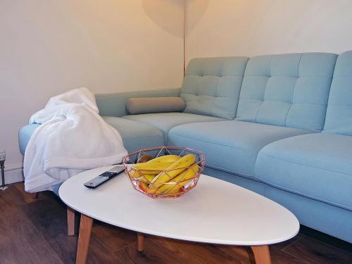 a bowl of bananas on a table in front of a blue couch at Great Orme - Uk2775 in Llandudno