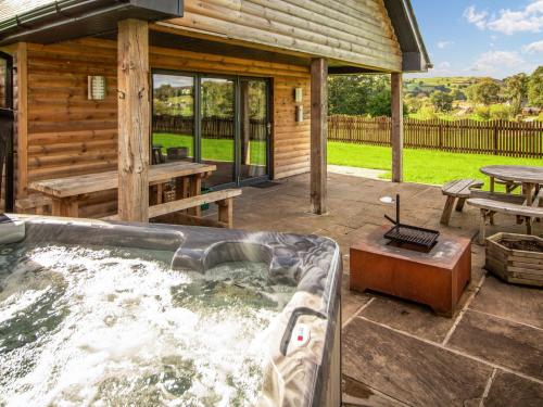 a hot tub in front of a log cabin at Caban Nant Ddu - Ukc8194 in Dolau