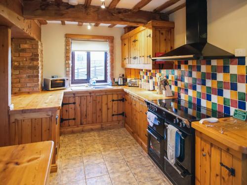 a kitchen with wooden cabinets and a stove top oven at The Threshing Barn - Ukc8847 in Timberland