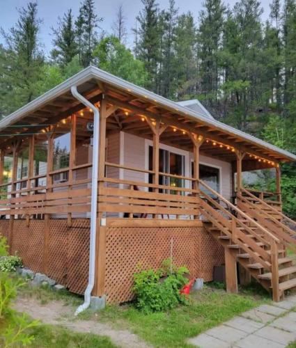 a home with a large deck with a porch at Refuge Boréal - Bord du lac paisible in Saint-Ambroise