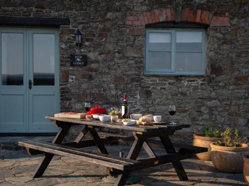 a picnic table with food and a bottle of wine at Rose Cottage - Ukc4693 in Kilkhampton