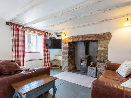 a living room with a stone fireplace and a couch at Fuchia in Marhamchurch