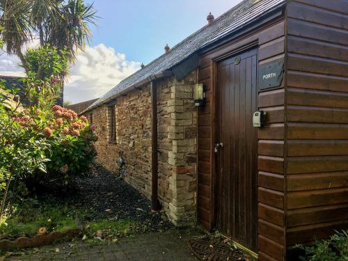 a brick building with a wooden door in a yard at Porth Cottage- W40885 in Perranporth