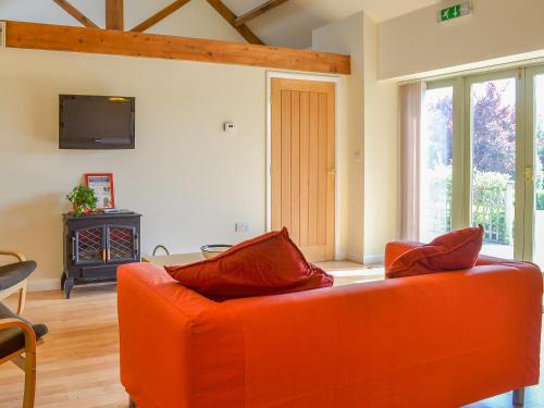 an orange couch in a living room with a tv at Stables Cottage-W42586 in Burn