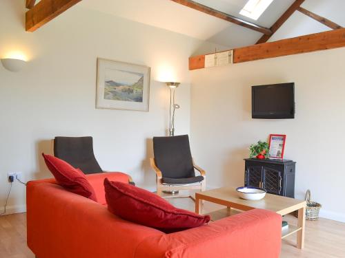 a living room with a red couch and a table at Stables Cottage-W42586 in Burn
