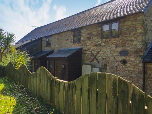 an old stone house with a wooden fence in front of it at Crantock Cottage- W40888 in Perranporth