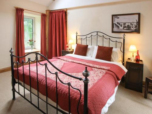 a bedroom with a large bed with a red comforter at Ty Cerbyd in Cilybebyll