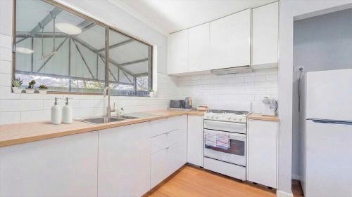 a kitchen with white cabinets and a large window at Nouveau Home in Epsom