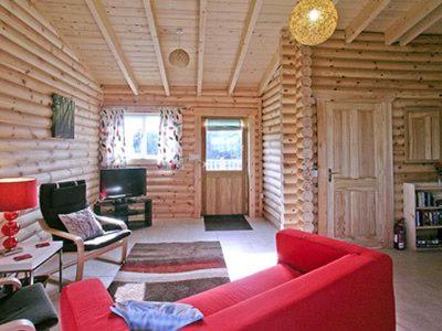a living room with a red couch in a log cabin at Partridge Lodge-W43008 in Burn