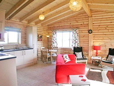 a living room with a red couch in a log cabin at Partridge Lodge-W43008 in Burn