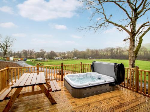 a hot tub on a deck with a picnic table at Buck Barn - Ukc8185 in Dolau