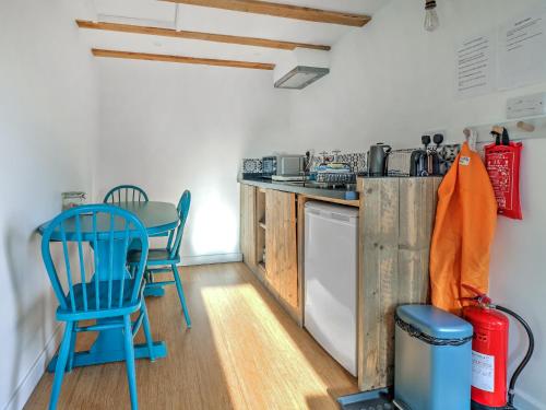 a kitchen with blue chairs and a table and a stove at Staddlestone Barn - Ukc8984 in Romsey