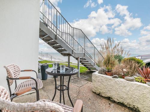 a patio with a table and chairs and a staircase at 17 Mount Brioni in Downderry