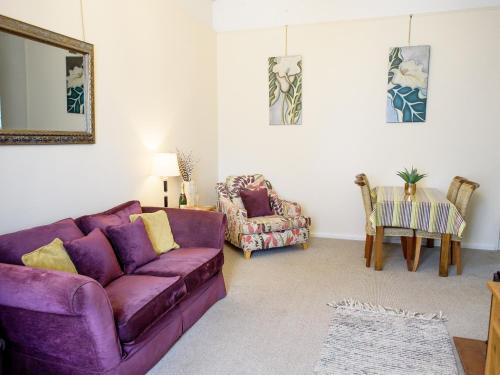 a living room with a purple couch and a table at Langetot in Bury Saint Edmunds