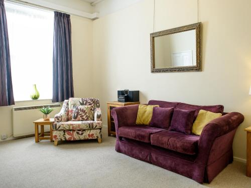 a living room with a purple couch and a chair at Langetot in Bury Saint Edmunds
