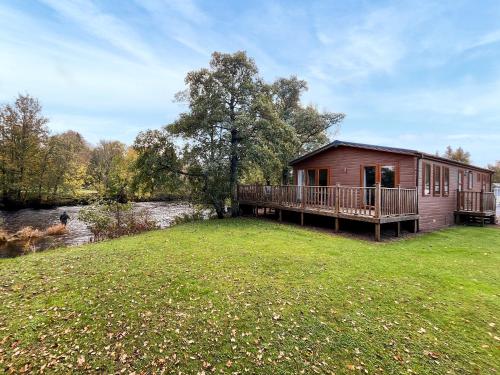 a log cabin with a deck and a river at The Ardle in Crieff