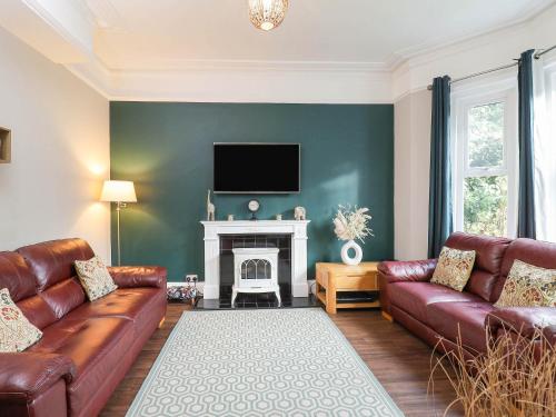 a living room with two leather couches and a fireplace at Kenmare Cottage in Shanklin