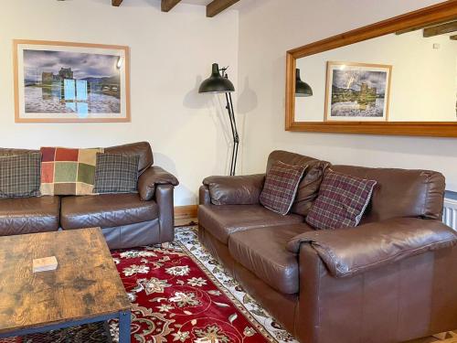 a living room with two leather couches and a table at Culrain Cottage in Fort Augustus