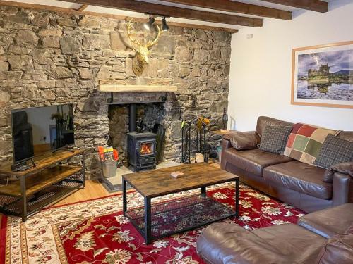 a living room with a couch and a stone fireplace at Culrain Cottage in Fort Augustus