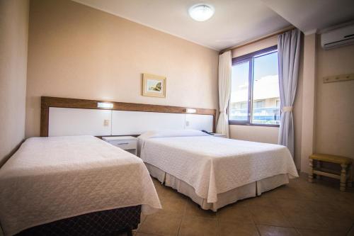 a hotel room with two beds and a window at Dunas Praia Hotel in Torres