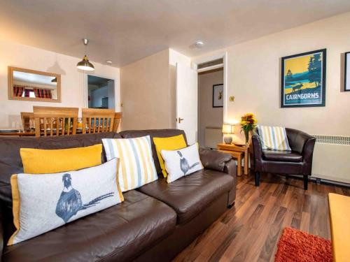 a living room with a brown leather couch with yellow pillows at The Osprey-Ukc5062 in Aviemore