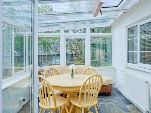 a conservatory with a wooden table and chairs at The Den - Ukc4937 in West Anstey