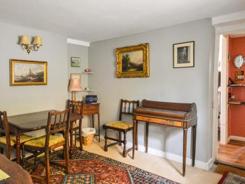 a dining room with a table and a piano at Grove Cottage in Yarmouth