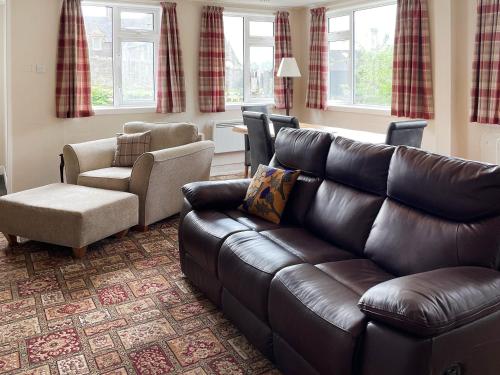 a living room with a leather couch and a chair at Crianlarich Cottage in Fort Augustus