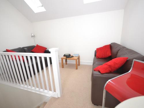 a living room with a brown couch and red pillows at The Sanctuary in Sandown