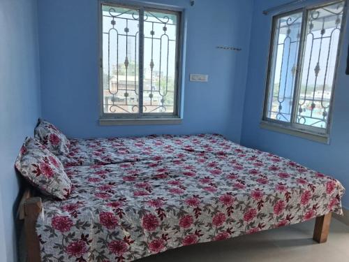 a bed in a room with two windows at Bhakta Bhawan in mayapur