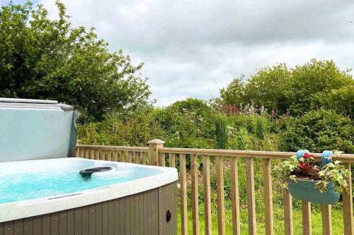 a hot tub sitting on a wooden fence at Holywell - Cwc in Perranporth