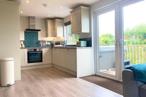 a kitchen with white cabinets and a sliding glass door at Holywell - Cwc in Perranporth
