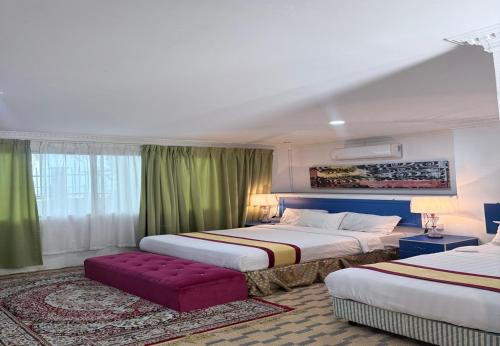 a hotel room with two beds and a red couch at Hotel Green Town Port Dickson in Port Dickson