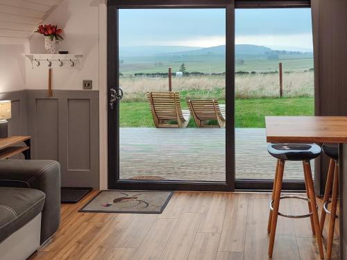 a living room with a table and a sliding glass door at Ben Rinnes - Ukc6028 in Newmill