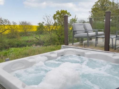 a hot tub with snow on a deck with a chair at Unwind 37 - Uk43980 in West Thirston