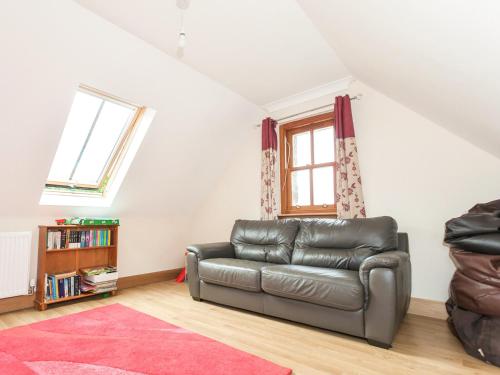a living room with a leather couch and a window at Appletree Cottage - Ukc6251 in Linlithgow