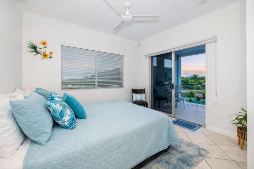 a bedroom with a bed with blue pillows and a balcony at Ocean-View Penthouse on The Strand, Townsville - 3 Bedrooms in North Ward