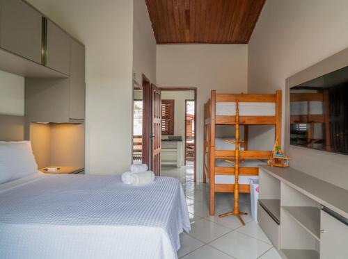 a bedroom with a white bed and a kitchen at Flat dboa in Jericoacoara