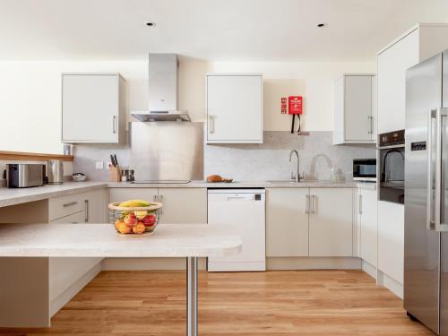 a kitchen with white cabinets and a bowl of fruit on a table at Emsdorf Lodge - Ukc5800 in Lundin Links