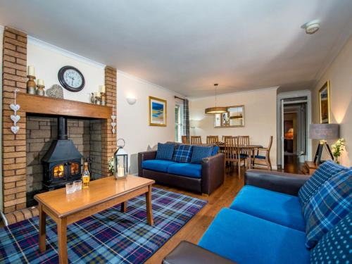 a living room with a blue couch and a fireplace at The Cairngorm - Ukc5051 in Aviemore
