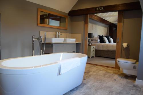 a bathroom with a tub and a sink and a bed at Briarfields Hotel in Titchwell