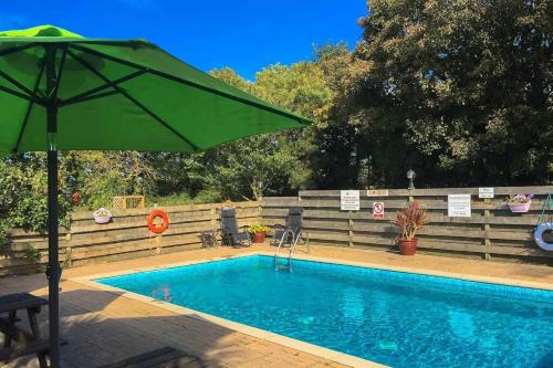 a swimming pool with a green umbrella next to it at Fistral Cottage - Cwc46839 in Perranporth