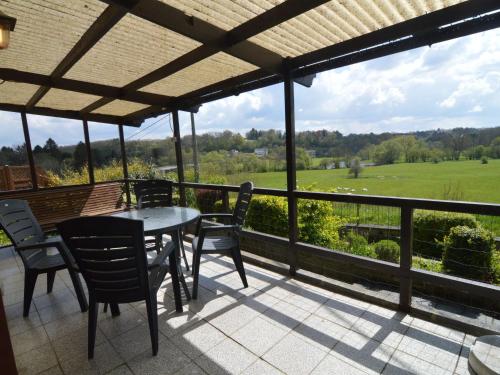 a patio with a table and chairs and a view of a field at Comfortable chalet in PetitHan with garden in Durbuy