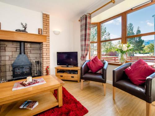 a living room with two chairs and a fireplace at The Stag-Ukc5066 in Aviemore