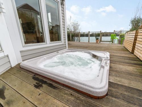 a hot tub on the deck of a house at Wrens Lake House in South Cerney