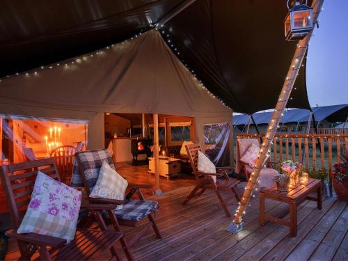 a tent with chairs and a table on a deck at 2 Lower Keat Glamping - Ukc4744 in Chardstock