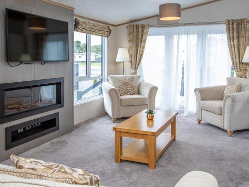 a living room with a fireplace and a tv at Rivendale 8 in St. Andrews