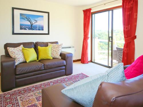 a living room with a brown couch with yellow pillows at Holly Cottage in Uckfield