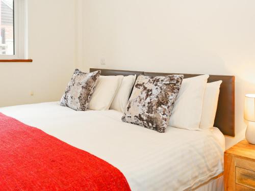 a bed with white pillows and a red blanket at Beech Cottage in Uckfield